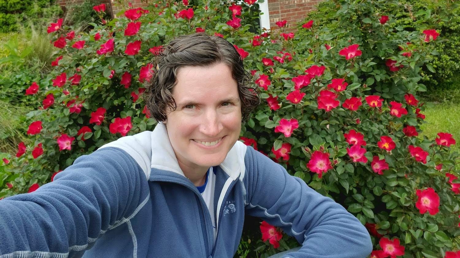 Anelle Ammons pictured in front of a red flower bush.