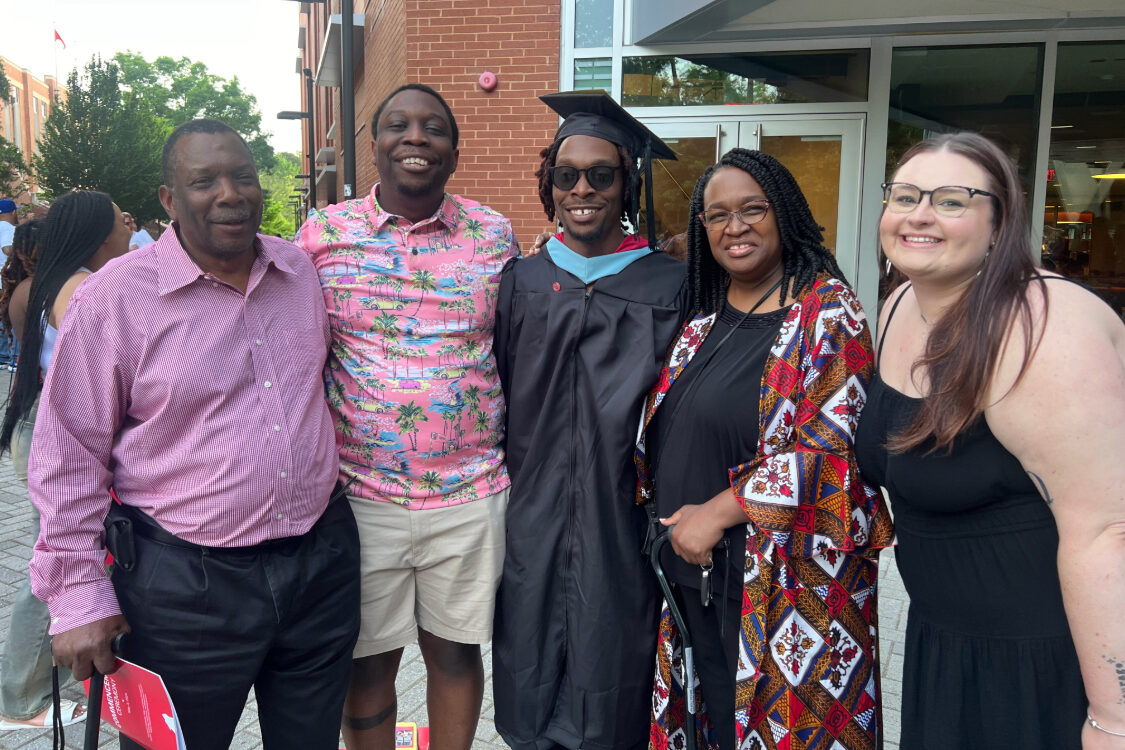 A group of people posing outdoors together following a graduation.